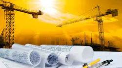 architectural plan on unseen table with construction equipment, such as cranes, in the background.