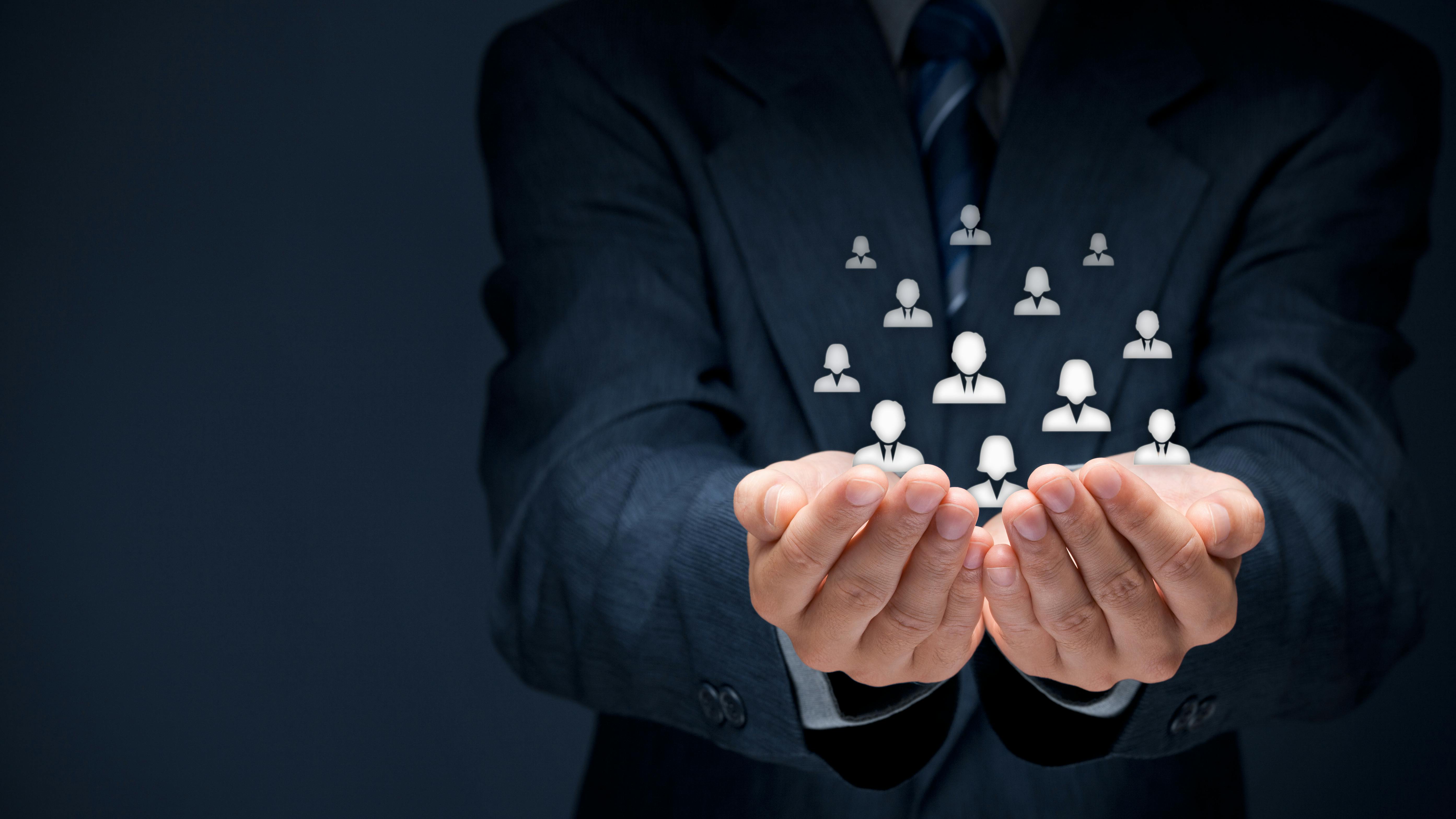Businessman holding glass cubes with icons representing group of people.
