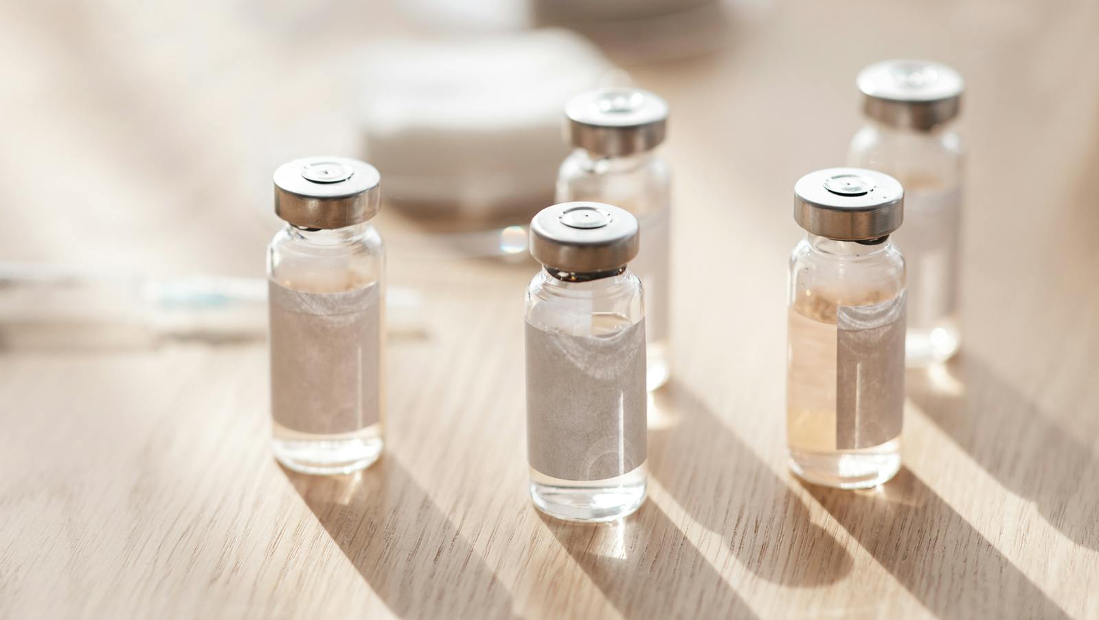 Ampoules, syringes and cotton pads on wooden table