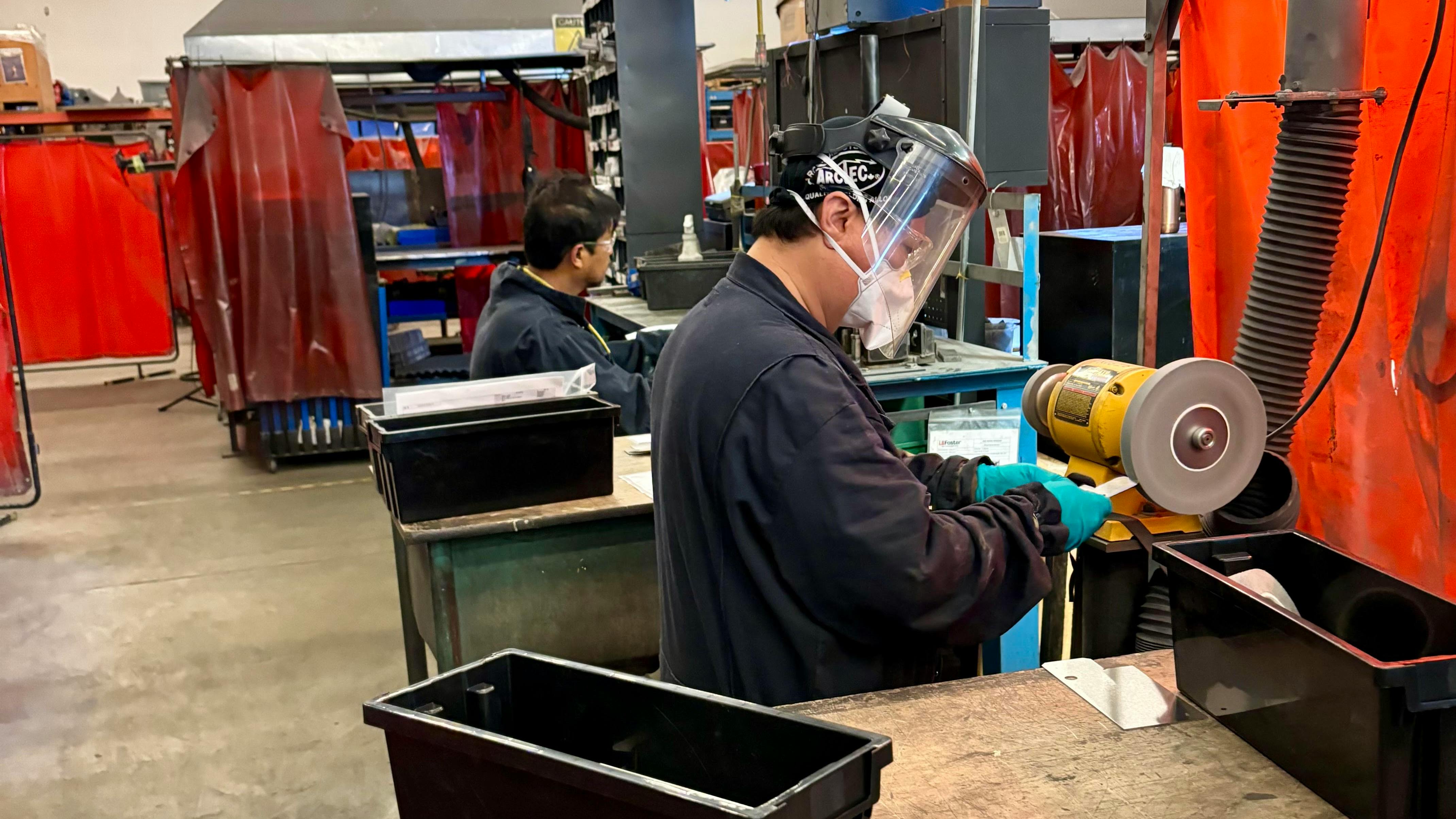 LB Foster Joemar Fortaleza bends inserts while co-worker Jose Zurbito deburs them on the soft wheel bench grinder.