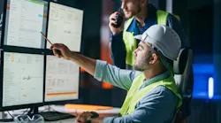 Two manufacturing leaders go over an ERP system in a factory.